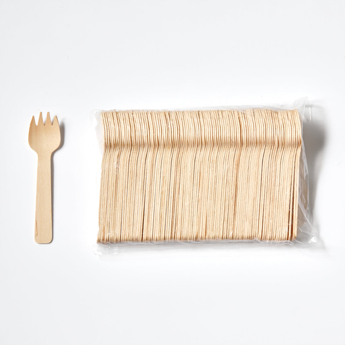 A pack of small disposable and compostable wooden sporks in clear plastic packaging, shown next to a single loose wooden spork on a clean white background.